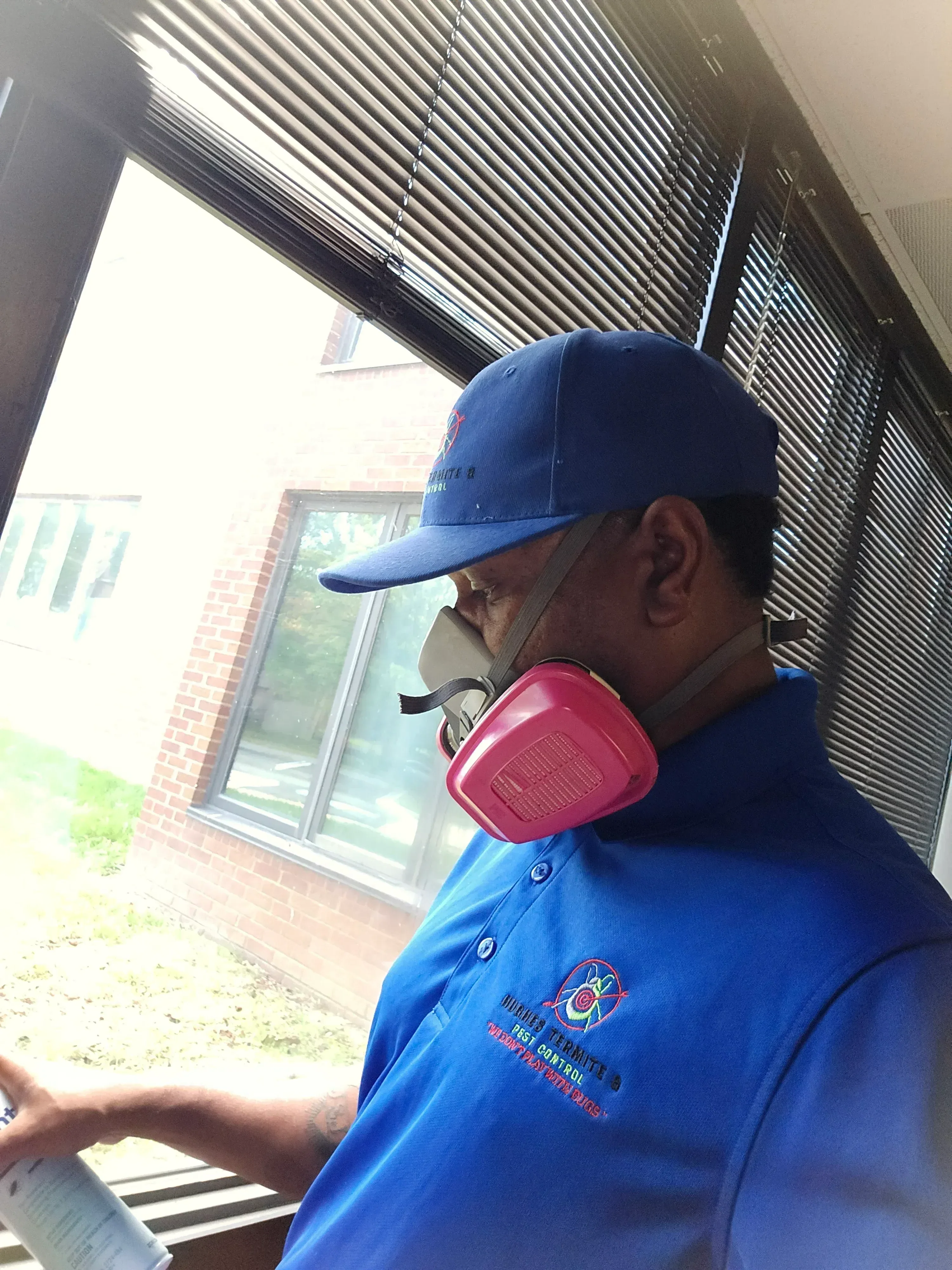 Pest control technician using thermal imaging camera on residential brick and metal siding exterior