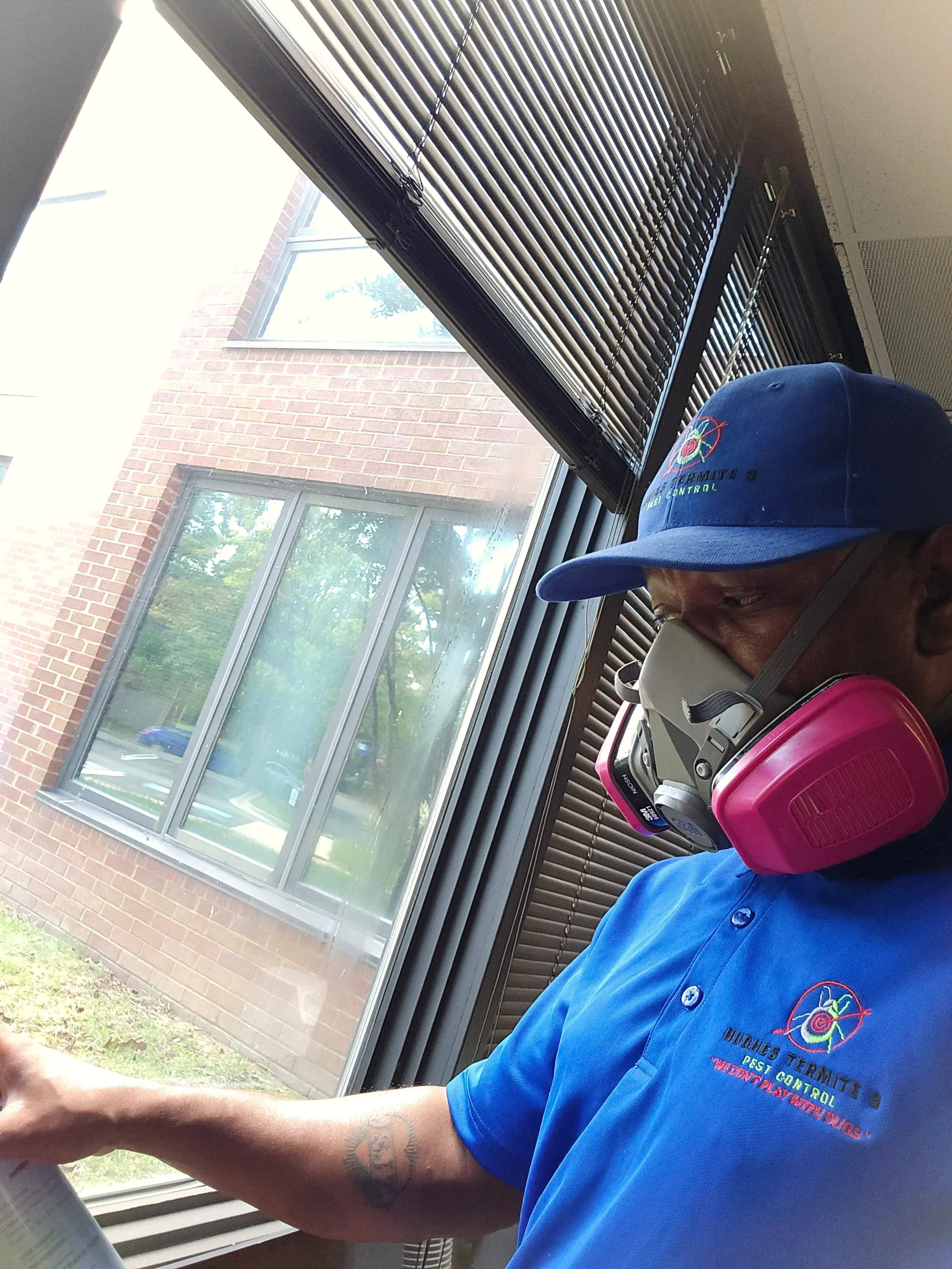 Pest control technician inspecting brick home exterior with windows and metal siding