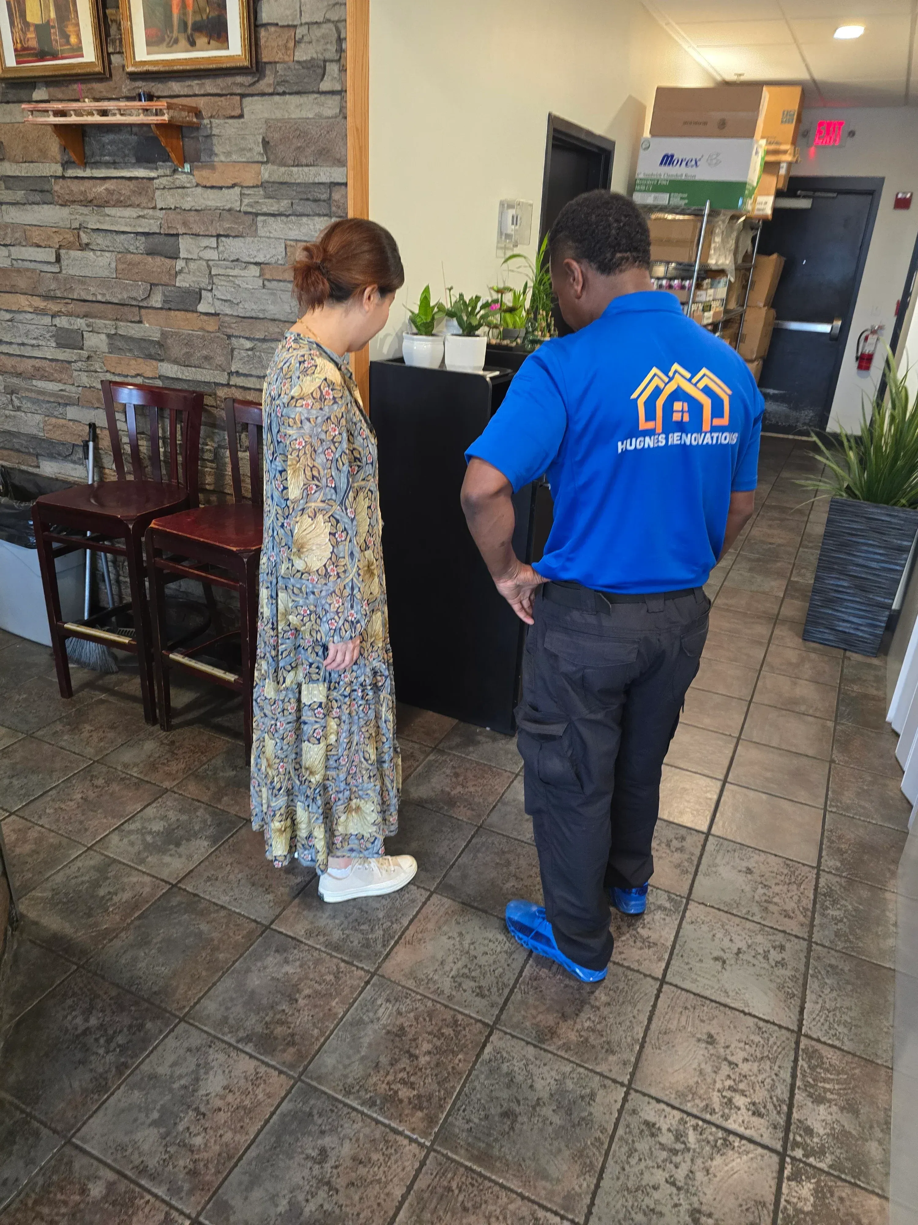 Pest control technician performing interior treatment in commercial space with tile flooring